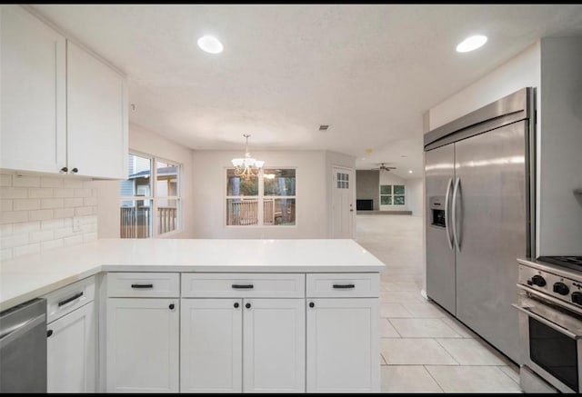 kitchen with white cabinetry, appliances with stainless steel finishes, kitchen peninsula, and hanging light fixtures