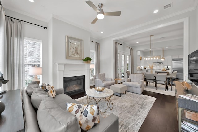 living room featuring ceiling fan, ornamental molding, and dark hardwood / wood-style floors