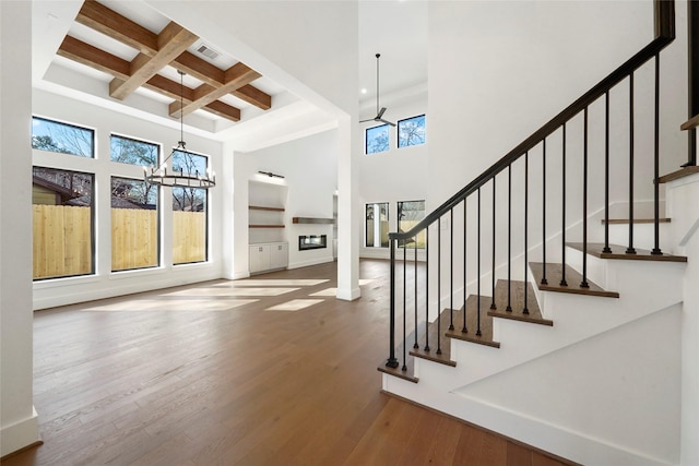 8545 Ridgepoint Dr, Houston, TX 77055 - unfurnished living room featuring a high ceiling, beamed ceiling, a chandelier, wood finished floors, and coffered ceiling
