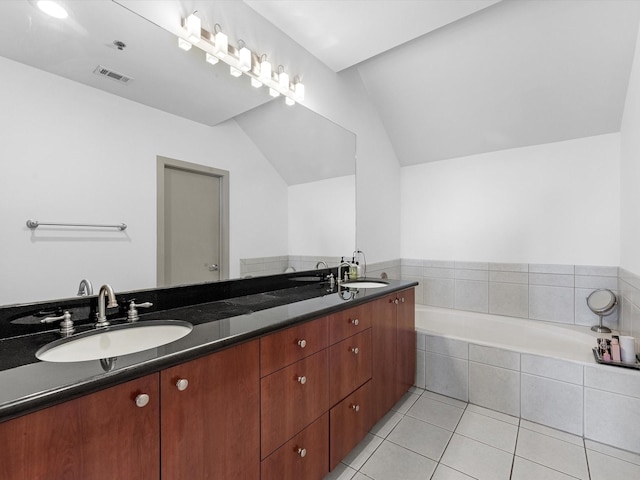 bathroom featuring lofted ceiling, tile patterned flooring, vanity, and tiled tub