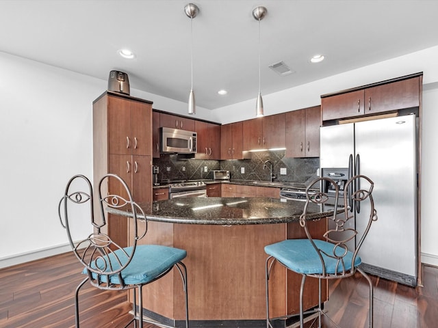 kitchen with stainless steel appliances, dark hardwood / wood-style floors, pendant lighting, and decorative backsplash