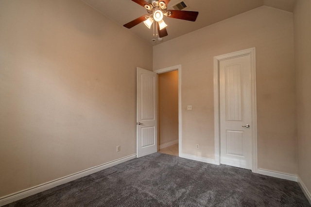 unfurnished bedroom with ceiling fan, lofted ceiling, and dark colored carpet