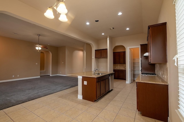 kitchen with light colored carpet, light stone countertops, sink, and a center island with sink