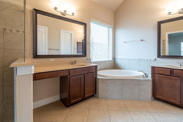 bathroom with tiled tub, vanity, lofted ceiling, and tile patterned flooring