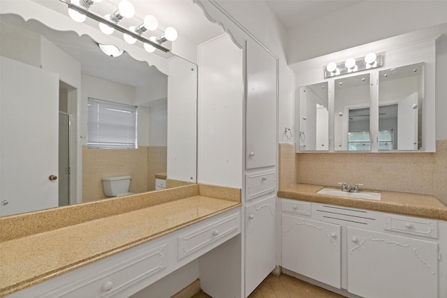 bathroom with tasteful backsplash, vanity, tile patterned flooring, and toilet