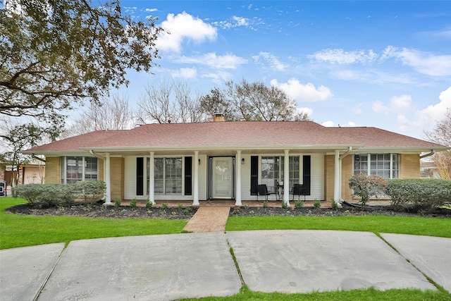 ranch-style house featuring covered porch and a front lawn