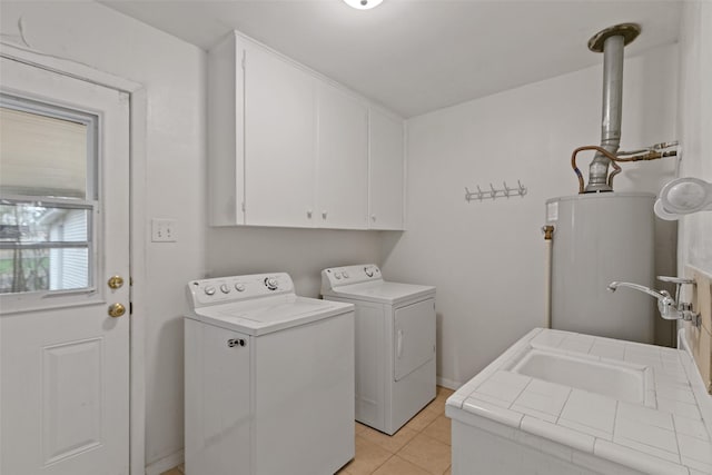 clothes washing area with cabinets, light tile patterned floors, washing machine and dryer, and gas water heater