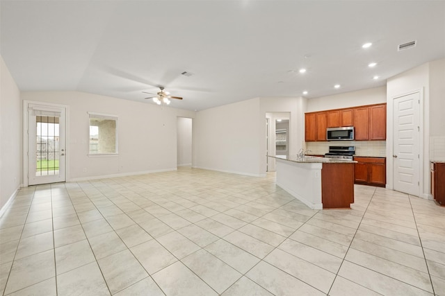 kitchen featuring light tile patterned floors, ceiling fan, stainless steel appliances, tasteful backsplash, and a center island with sink