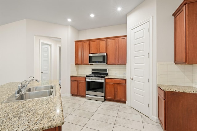 kitchen with light stone counters, sink, stainless steel appliances, and light tile patterned flooring