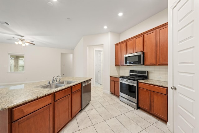 kitchen with sink, decorative backsplash, light tile patterned floors, light stone counters, and stainless steel appliances