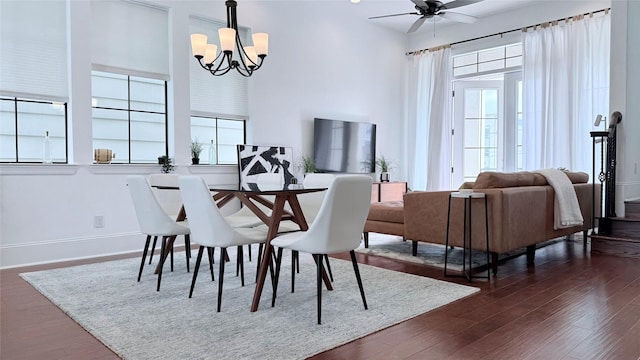 dining space with ceiling fan with notable chandelier and dark hardwood / wood-style flooring