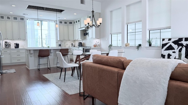 living room with plenty of natural light, dark wood-type flooring, sink, and a chandelier