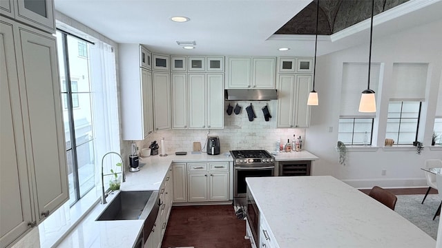 kitchen with light stone counters, gas range, sink, and hanging light fixtures