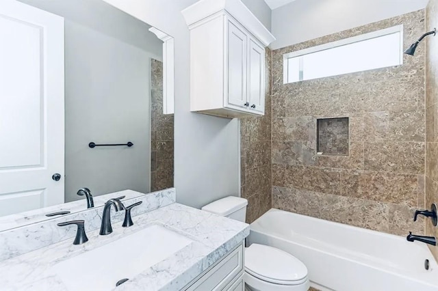 full bathroom featuring tiled shower / bath combo, vanity, and toilet