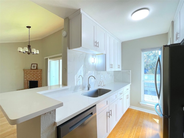 kitchen featuring pendant lighting, light countertops, appliances with stainless steel finishes, a sink, and a peninsula