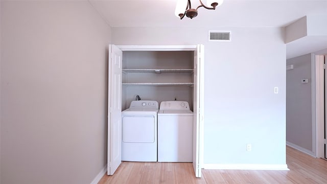 washroom featuring laundry area, visible vents, baseboards, light wood-style floors, and washing machine and dryer