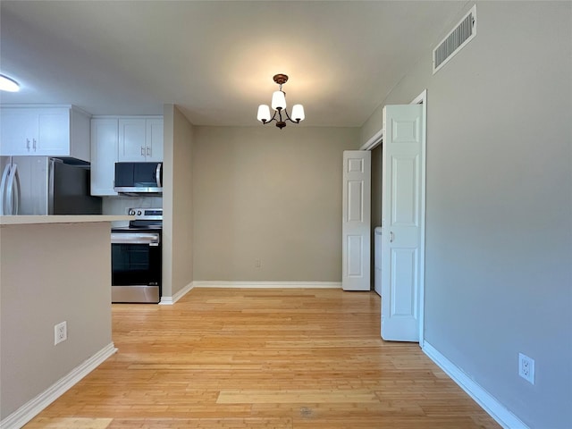 kitchen featuring stainless steel appliances, light countertops, visible vents, white cabinets, and a chandelier