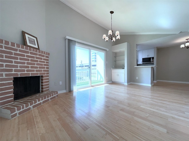 unfurnished living room featuring baseboards, light wood-style floors, ornamental molding, an inviting chandelier, and a brick fireplace