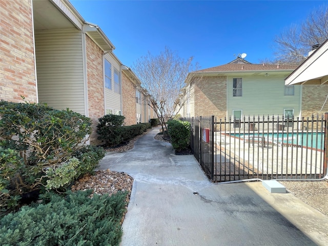 view of home's exterior featuring brick siding, fence, and a fenced in pool