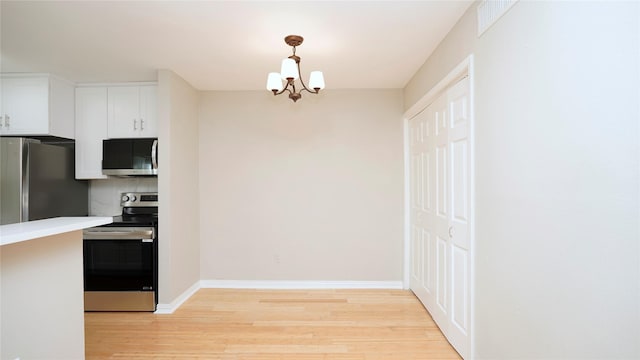 2300 Augusta Dr Unit 22, Houston, TX 77057 - kitchen with stainless steel appliances, light wood-style floors, a chandelier, white cabinetry, and baseboards