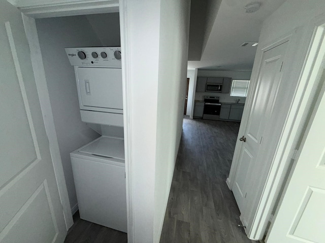 washroom featuring stacked washer / drying machine and dark hardwood / wood-style floors