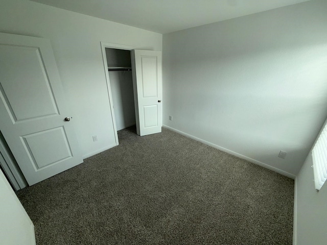 unfurnished bedroom with dark colored carpet and a closet