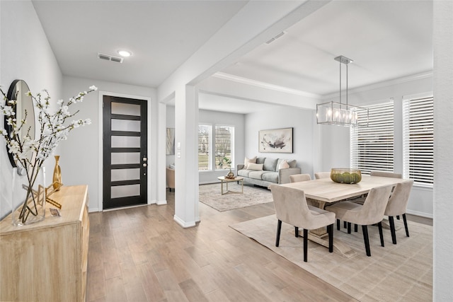 foyer entrance with crown molding, a chandelier, and light hardwood / wood-style floors