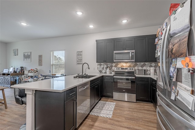 kitchen featuring a peninsula, appliances with stainless steel finishes, light countertops, and a sink