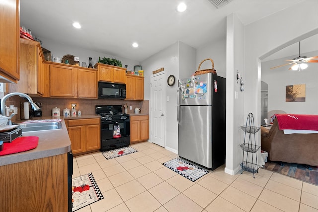 kitchen featuring arched walkways, a sink, decorative backsplash, ceiling fan, and black appliances