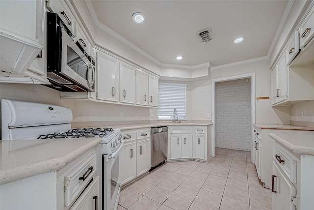 kitchen with sink, light tile patterned floors, appliances with stainless steel finishes, white cabinets, and crown molding