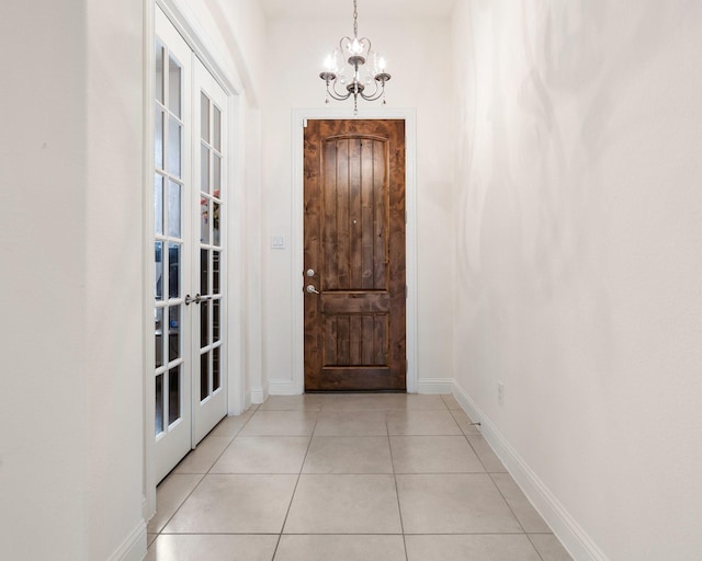 entryway with a chandelier, light tile patterned floors, and baseboards