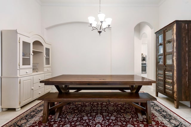 unfurnished dining area featuring crown molding, light tile patterned floors, arched walkways, and a notable chandelier