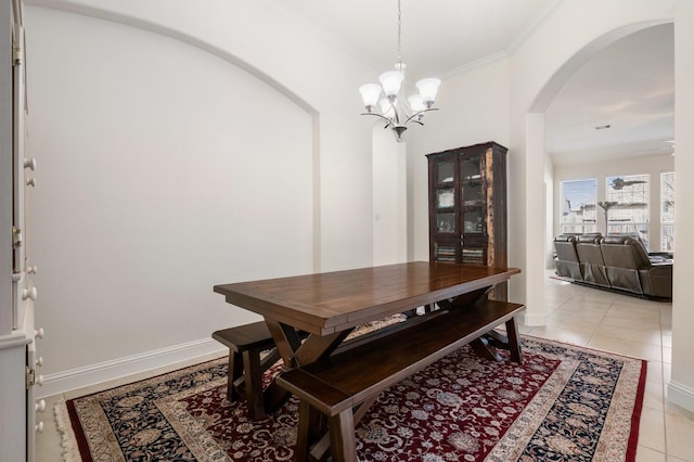 dining area with light tile patterned flooring, arched walkways, an inviting chandelier, and crown molding