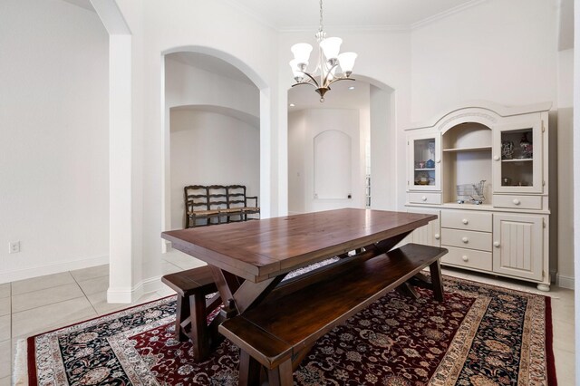 dining space featuring light tile patterned floors, baseboards, arched walkways, a notable chandelier, and ornamental molding