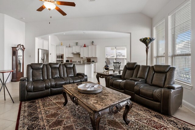 living area with arched walkways, vaulted ceiling, a ceiling fan, and light tile patterned flooring