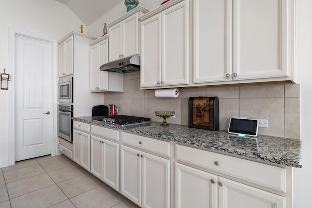 9518 Brannok Ln, Tomball, TX 77375 - kitchen featuring stainless steel appliances, under cabinet range hood, tasteful backsplash, stone countertops, and vaulted ceiling