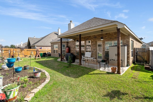 back of house with a yard, a patio area, a fenced backyard, and brick siding