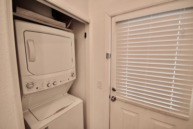 laundry area with stacked washer / drying machine and laundry area