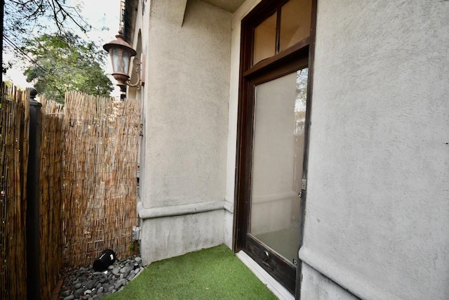 entrance to property featuring fence and stucco siding