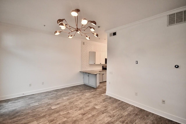 interior space with crown molding, visible vents, a notable chandelier, and wood finished floors