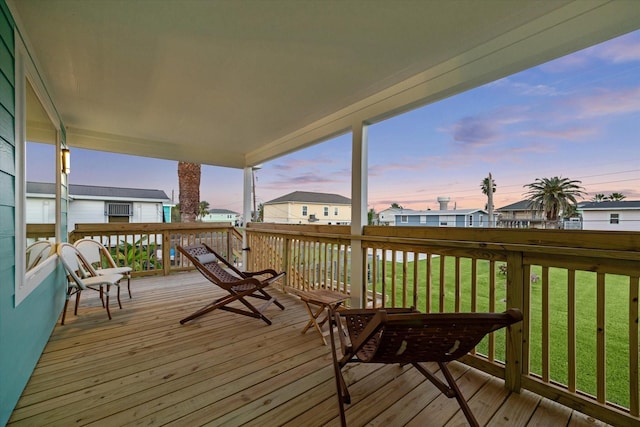 deck at dusk featuring a lawn