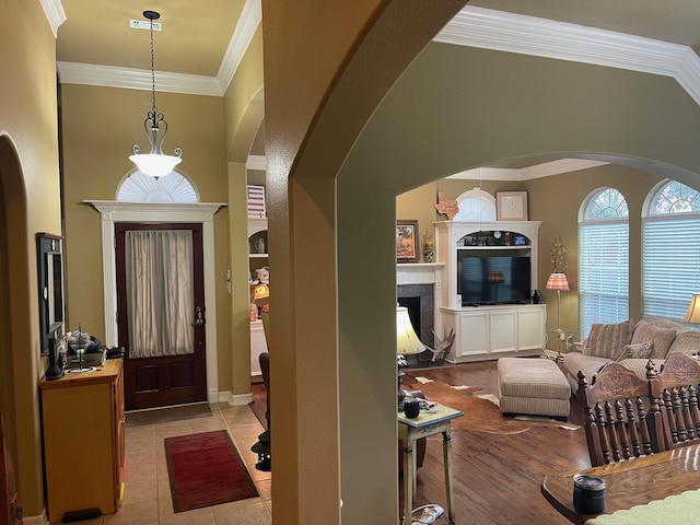 entryway featuring light hardwood / wood-style flooring, ornamental molding, and a fireplace