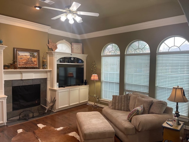 living room featuring ornamental molding, plenty of natural light, dark wood-type flooring, and a tile fireplace