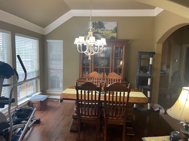 dining room featuring dark wood-type flooring, vaulted ceiling, crown molding, and an inviting chandelier