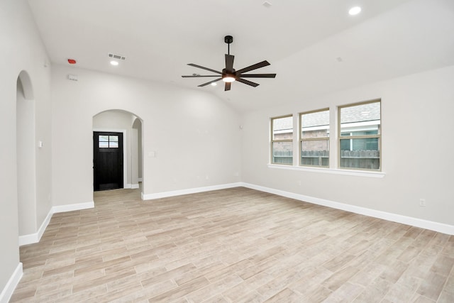 empty room with ceiling fan, lofted ceiling, and light wood-type flooring