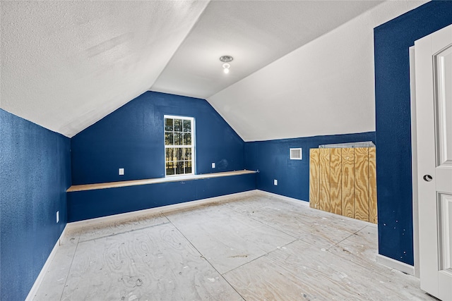 additional living space featuring lofted ceiling and a textured ceiling