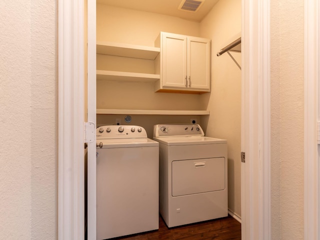 laundry room featuring dark hardwood / wood-style floors, washer and clothes dryer, and cabinets