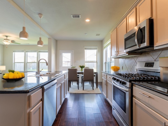 kitchen featuring appliances with stainless steel finishes, decorative light fixtures, sink, decorative backsplash, and dark wood-type flooring