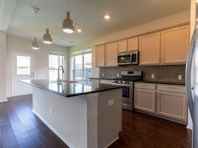 kitchen with appliances with stainless steel finishes, hanging light fixtures, sink, and a center island with sink