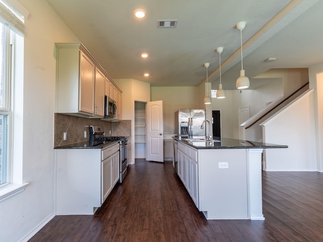 kitchen with pendant lighting, white cabinetry, appliances with stainless steel finishes, and a kitchen island with sink